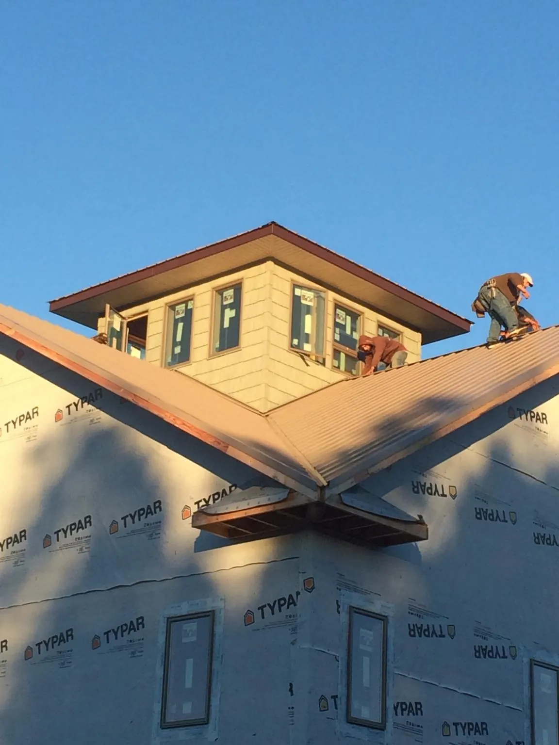 Roofers working around a rooftop cupola on a new metal roof at sunset — Roof Waterproofing in Enterprise by Roofing Brothers